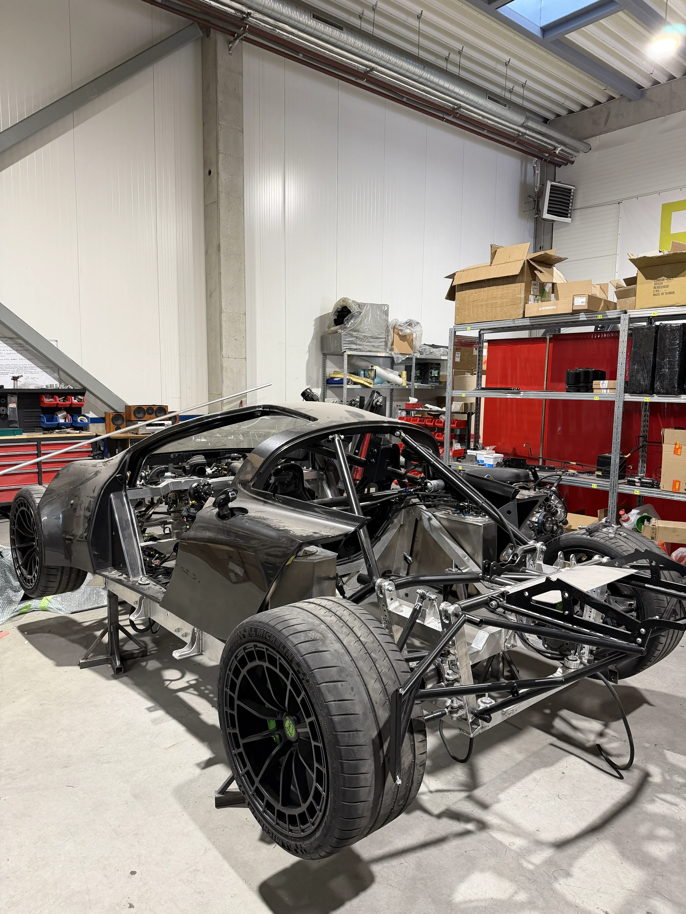 The RR01 as a bare chassis on stands in the Kaunas workshop, body panels off